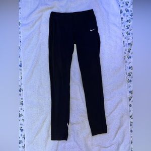 Black Nike leggings with a a big symbol on the bottom left leg.